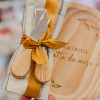 Conjunto com guardanapo e talheres de queijo com cabos de madeira e fita amarela.