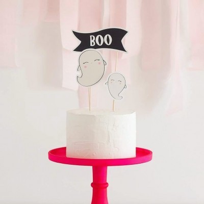 Bolo branco com toppers de fantasmas e bandeira 'BOO' sobre suporte vermelho