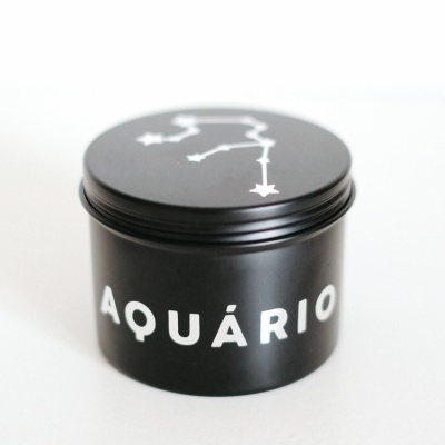 Embalagem preta cilíndrica com texto e constelação branca.