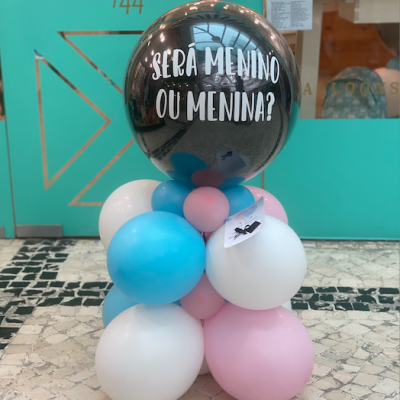 Arranjo de balões para festa de revelação de género com balões azul, rosa, branco e preto com texto.