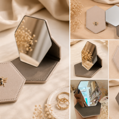 Espelho portátil hexagonal em tecido cinza com abelha dourada, aberto e fechado, ambiente com tecido bege e flores secas.