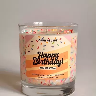 Vela decorada com confeitos coloridos e etiqueta de aniversário em frasco de vidro