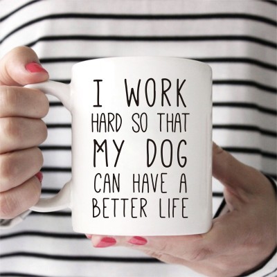 Caneca branca com texto em preto segurada por mãos com unhas pintadas de rosa