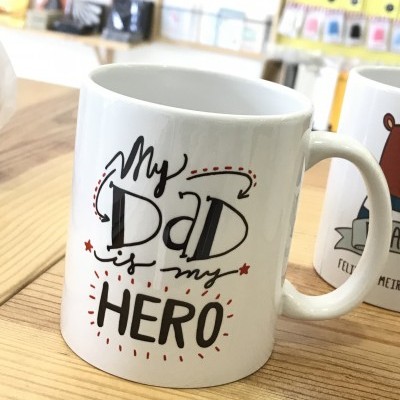 Caneca branca com frase My Dad is my HERO numa mesa de madeira