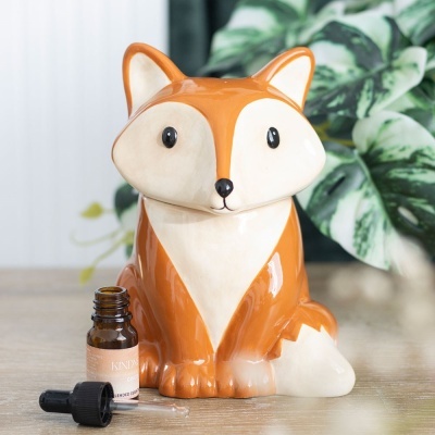 Figura decorativa em cerâmica de raposo castanho e branco com um frasco de vidro castanho ao lado