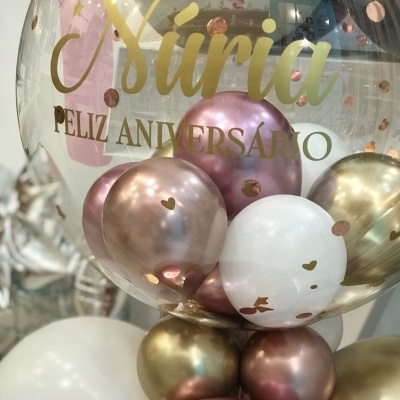 Balão transparente decorado com balões interiores coloridos e texto de feliz aniversário.