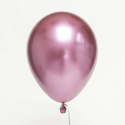 Balão rosa metálico brilhante amarrado com fita sobre fundo branco