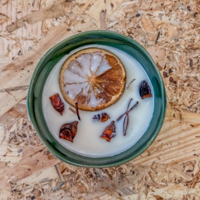 Vela branca em cerâmica verde com limão seco e flores decorativas