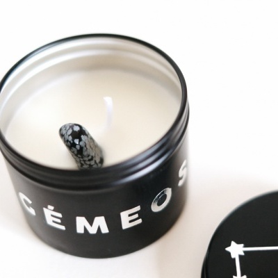 Vela preta com pavio decorado e texto em branco num fundo branco