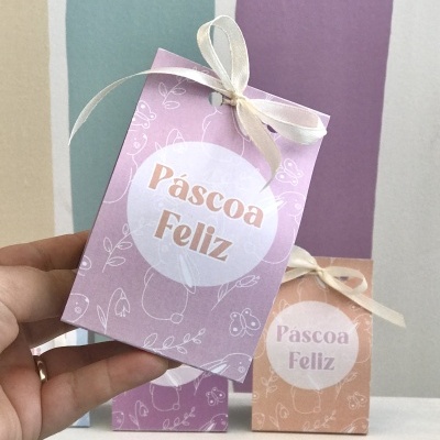 Caixas de papel decorativas para Páscoa com texto 'Páscoa Feliz', em rosa e laranja claro, com laços de fita branca