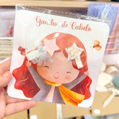 Ganchos de cabelo em forma de estrelas brilhantes em embalagem com desenho de menina ruiva