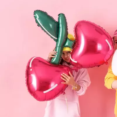 Balões em forma de cerejas vermelhas com folhas verdes numa mão