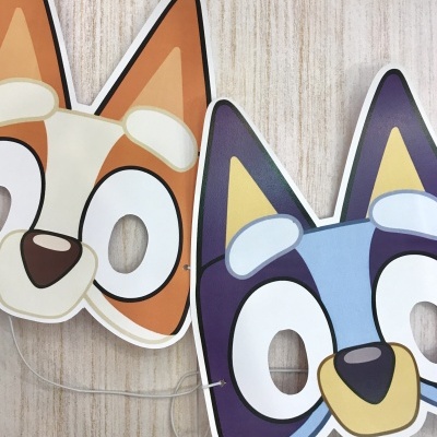 Máscaras de cães cartoon em papel com olhos recortados, castanho e roxo, sobre madeira clara
