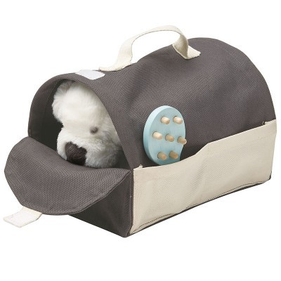 Bolsa de transporte castanha e bege para animais com uma pega e disco azul com peças de madeira na lateral, peluche branco visível