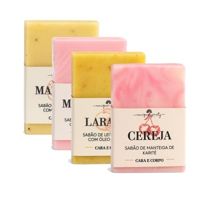 Quatro sabonetes coloridos amarelos e rosas com embalagens brancas e texto