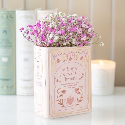 vaso em forma de livro cor de rosa com flores artificiais rosas e brancas