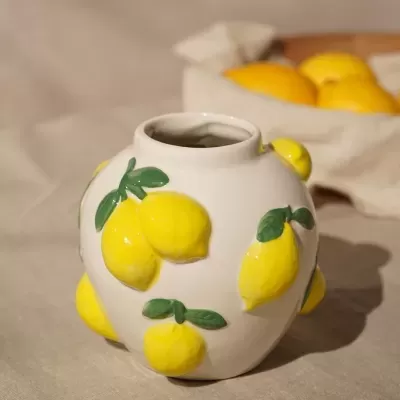 Vaso de cerâmica branca com limões amarelos em relevo