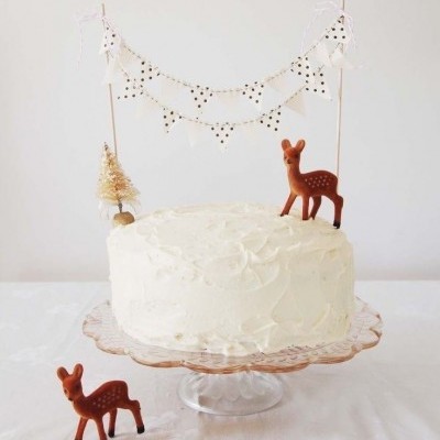 Bolo branco decorado com veados castanhos, árvore dourada e bandeirinhas brancas com pontos pretos