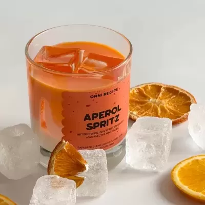 Vela Aperol Spritz em copo de vidro com fatias e cubos de laranja e cubos de gelo