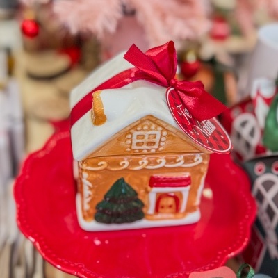 Casinha decorativa de Natal em cerâmica com fita vermelha num prato vermelho