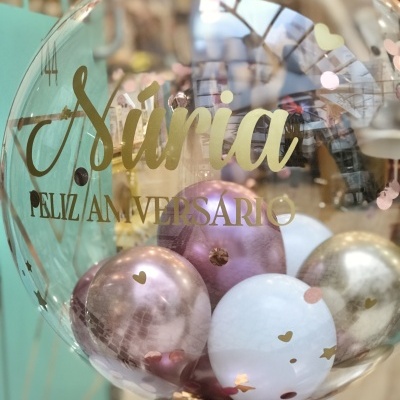 Balão transparente com escrita dourada e balões coloridos dentro
