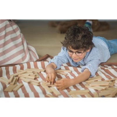 Menino deitado no chão a brincar com blocos de madeira