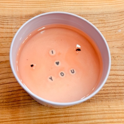 Vela cor-de-rosa com frase decorativa I ♥ YOU numa lata branca sobre madeira clara