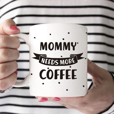 Caneca branca com texto 'MOMMY NEEDS MORE COFFEE' e padrão de pontos pretos