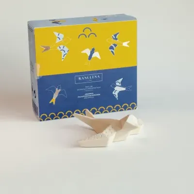 Caixa azul e amarela da MANULENA com peça decorativa branca em forma de andorinha
