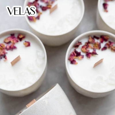 Velas brancas em recipientes de cerâmica com pétalas secas e pavios de madeira