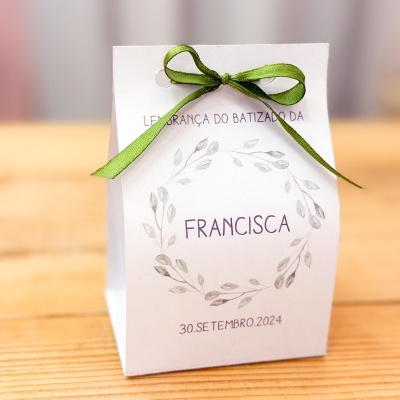 Embalagem branca com laço verde e texto de batizado