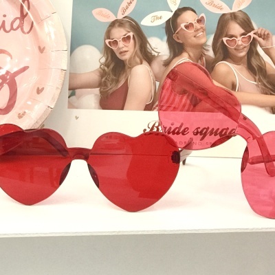 Óculos de sol em forma de coração vermelhos e rosa com fundo festivo