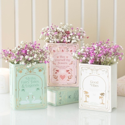Três vasos cerâmicos decorativos com flores e textos em inglês sobre uma superfície branca
