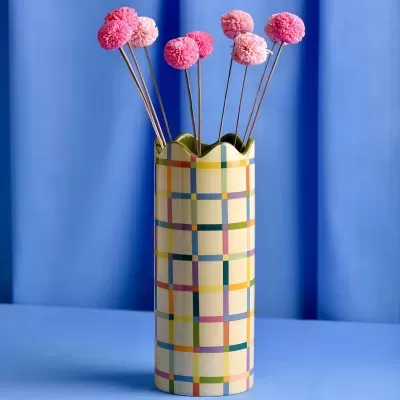 Vaso cerâmico com padrão xadrez e flores decorativas rosas e vermelhas.