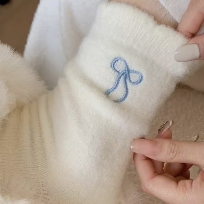 Manga de camisola branca de malha com bordado azul e mãos femininas