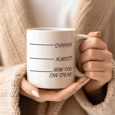 Caneca branca com texto em inglês segurada por mãos femininas com casaco bege