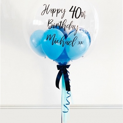 Balão transparente com balões azuis dentro e texto de aniversário