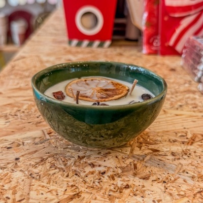 Vela decorativa em recipiente de cerâmica verde escuro com fatia de citrino seca