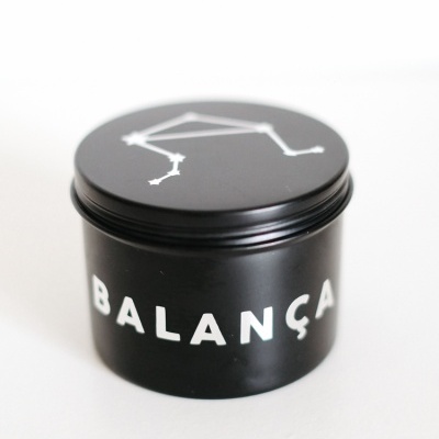 Frasco preto cilíndrico com texto BALANÇA e constelação branca na tampa