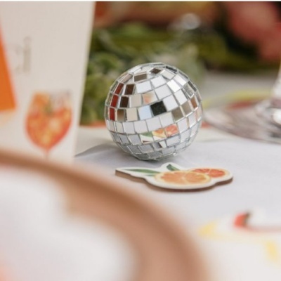 Bola decorativa espelhada sobre mesa com decoração e imagens de frutas