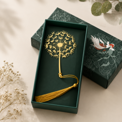 Marcador de página dourado com tassel amarelo numa caixa verde escura decorada