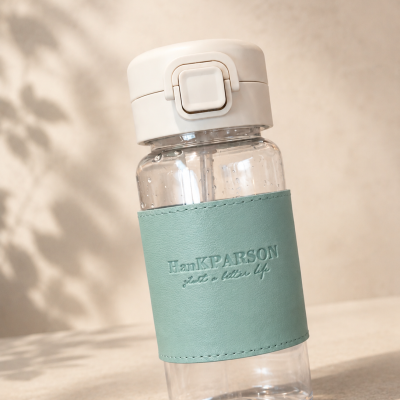 Garrafa de plástico transparente com capa verde e tampa branca