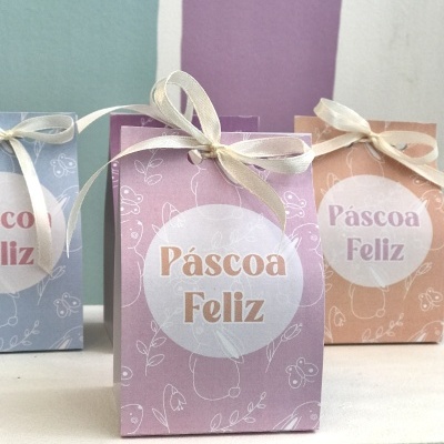 Sacolas de papel coloridas com texto Páscoa Feliz e laços de fita