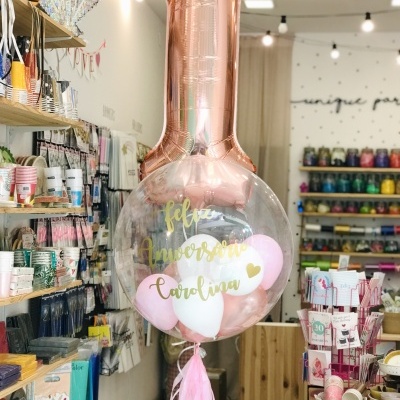 Balão de aniversário rosa dourado e transparente com texto para Carolina numa loja de artigos para festas