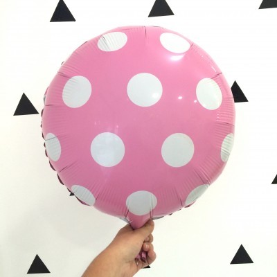 Balão rosa com bolinhas brancas sendo segurado por uma mão