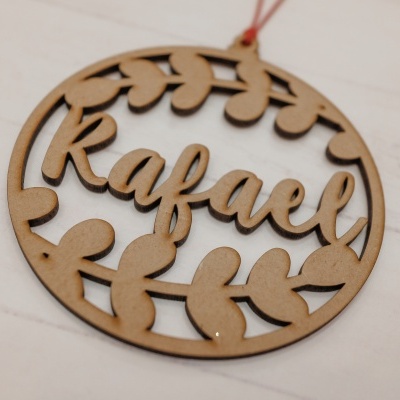Enfeite redondo de madeira com nome Rafael e padrão de folhas