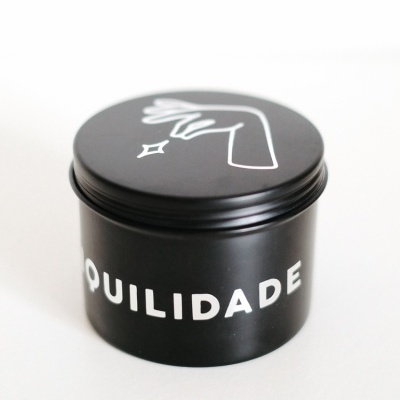 Embalagem preta cilíndrica com tampa, com texto e ilustração em branco