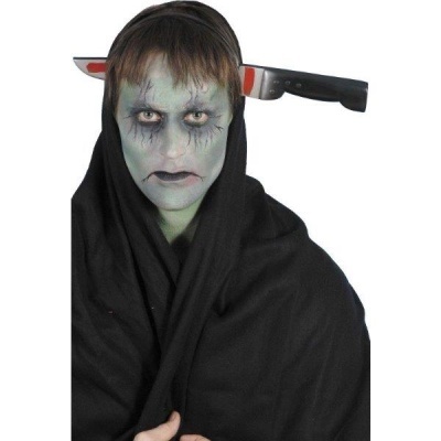 Pessoa com maquilhagem esverdeada, tecido preto e faca aparente atrás da cabeça