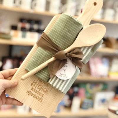 Conjunto de cozinha com tábua de madeira, colher de pau e panos risca verde e branca, com etiqueta 'PARA TI COM AMOR'.