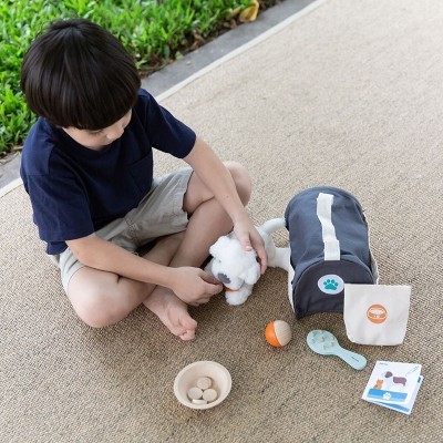 Criança a brincar com brinquedo de cão de peluche e acessórios num tapete